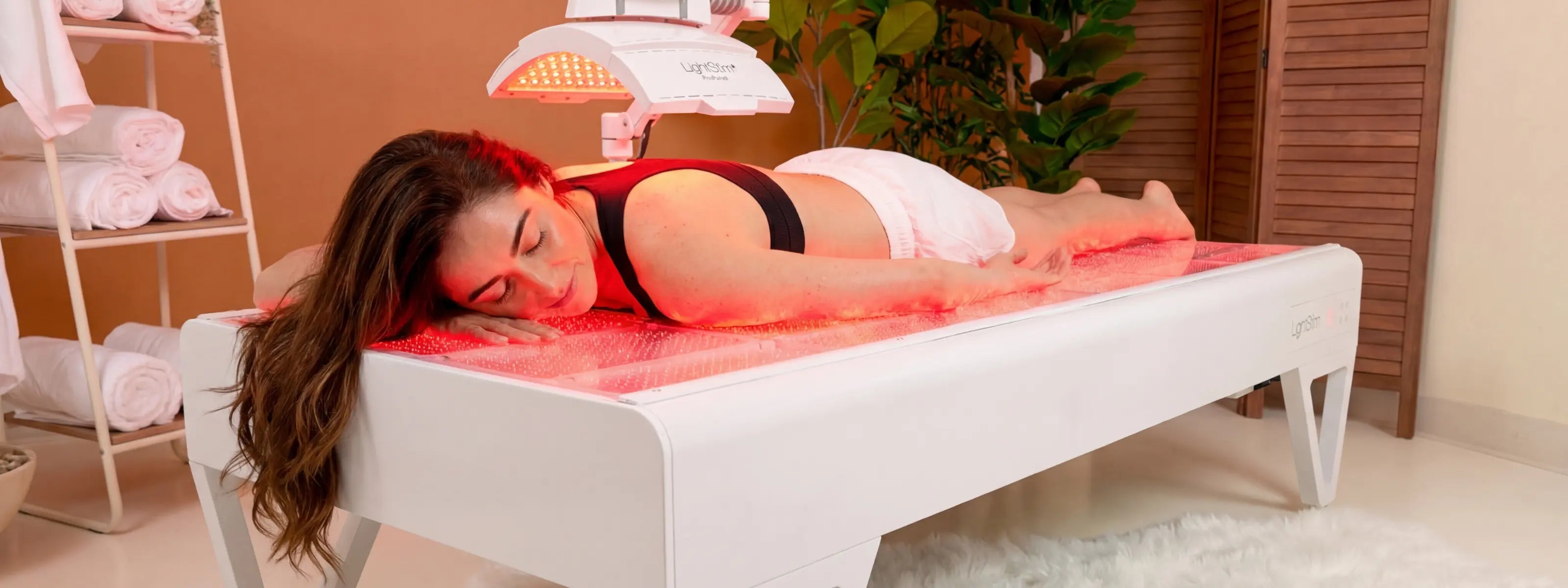 Woman relaxing on a LightStim Red Light therapy bed during a session at Body Reset Montecito